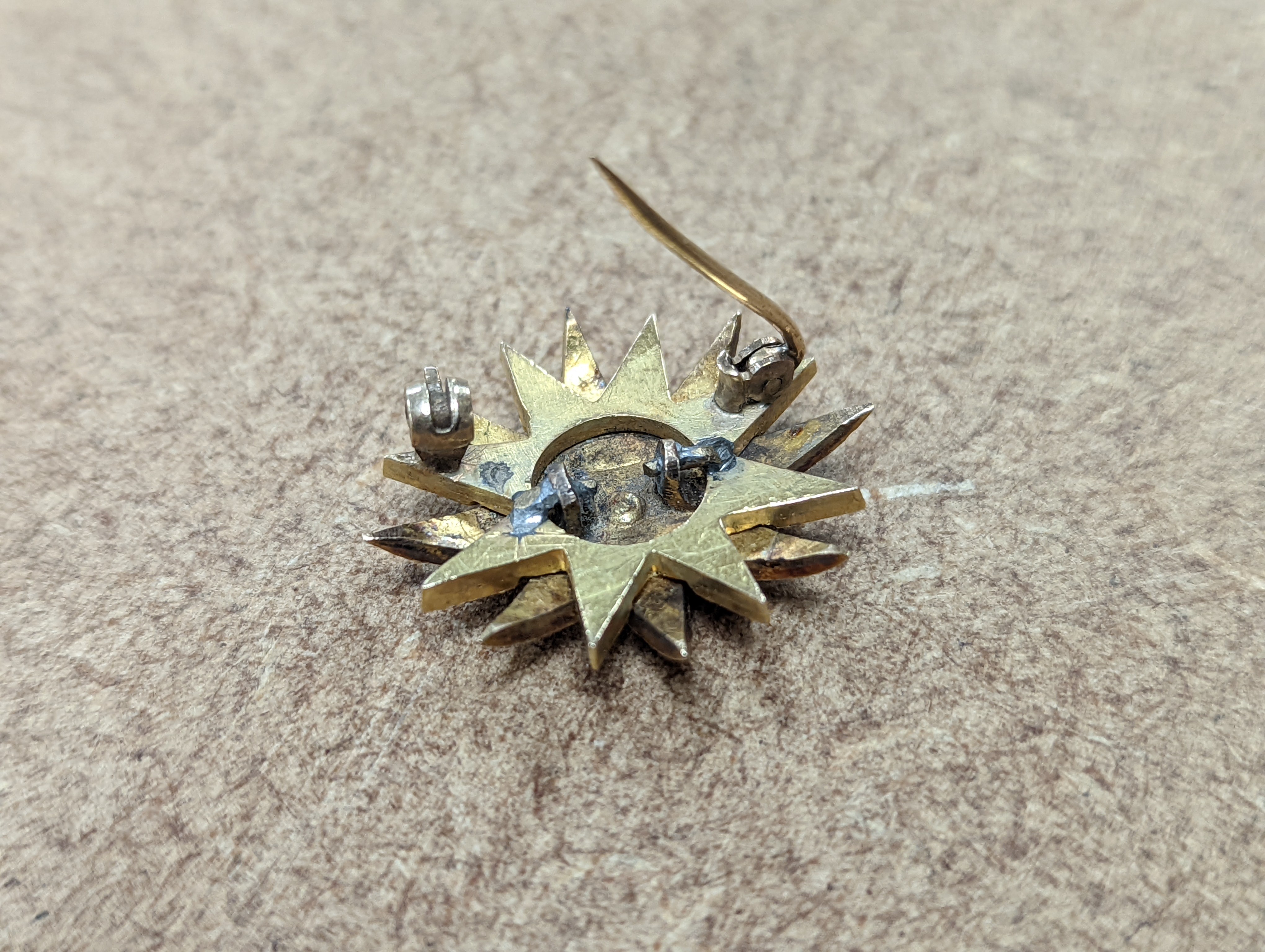 An Edwardian yellow metal, graduated split pearl and single stone diamond set starburst brooch(adapted?), 24mm, gross weight 6.5 grams.